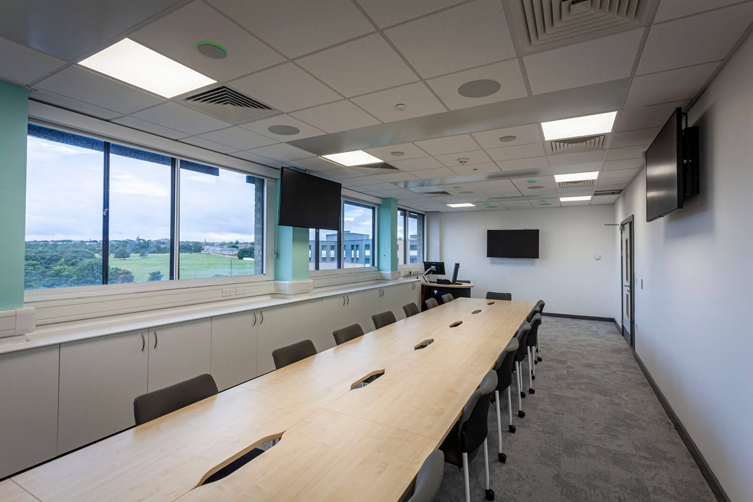 A seminar room with bench seating and display screen, one of the varied spaces the ventilation had to serve